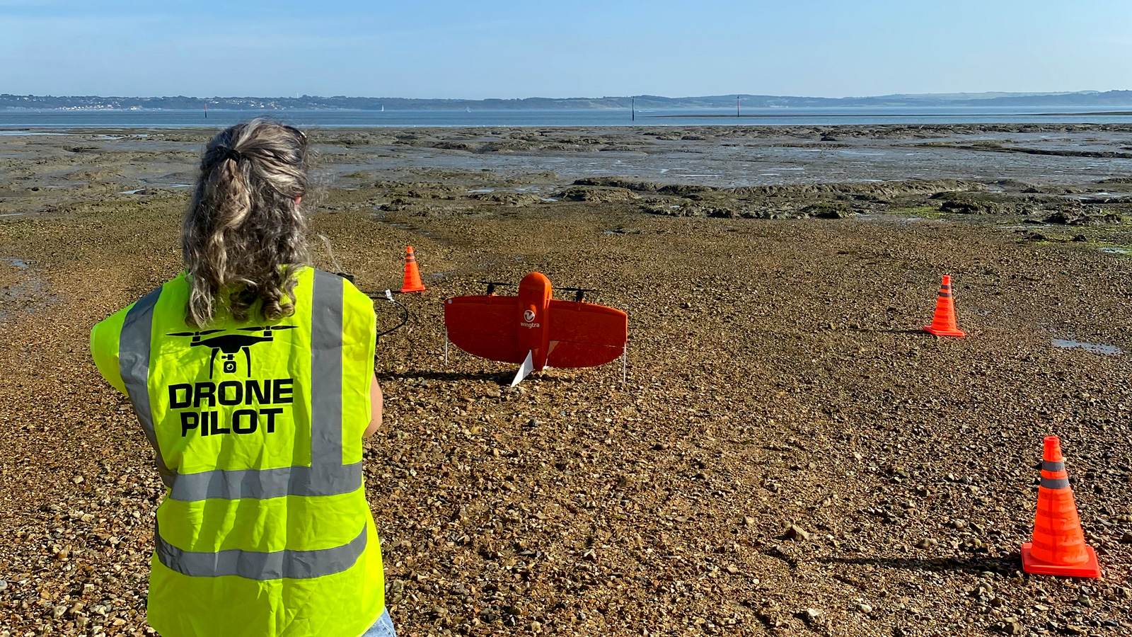 Pilot in bright vest watching the VTOL drone take off